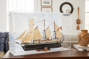 historic lego toy ship in a display case on a wooden surface with decorative items in the background.