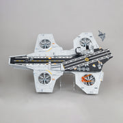 A toy model on a display stand of a LEGO Helicarrier, featuring a white and gray hull with black flight deck markings, orange accent details, and a small gray fighter jet attached to the rear