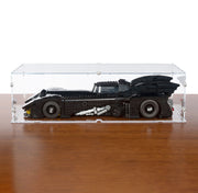 A black LEGO Batman vehicle displayed inside a clear acrylic storage box on a wooden tabletop