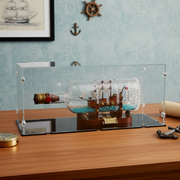 lego ship in a bottle inside a glass display case on a wooden table.