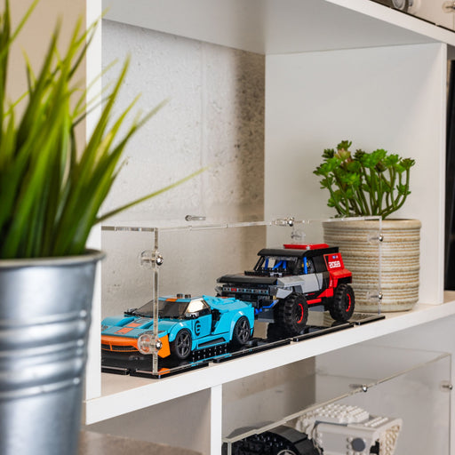 Toy cars lego speed champions x2 on a shelf with plants and a clear acrylic display case.
