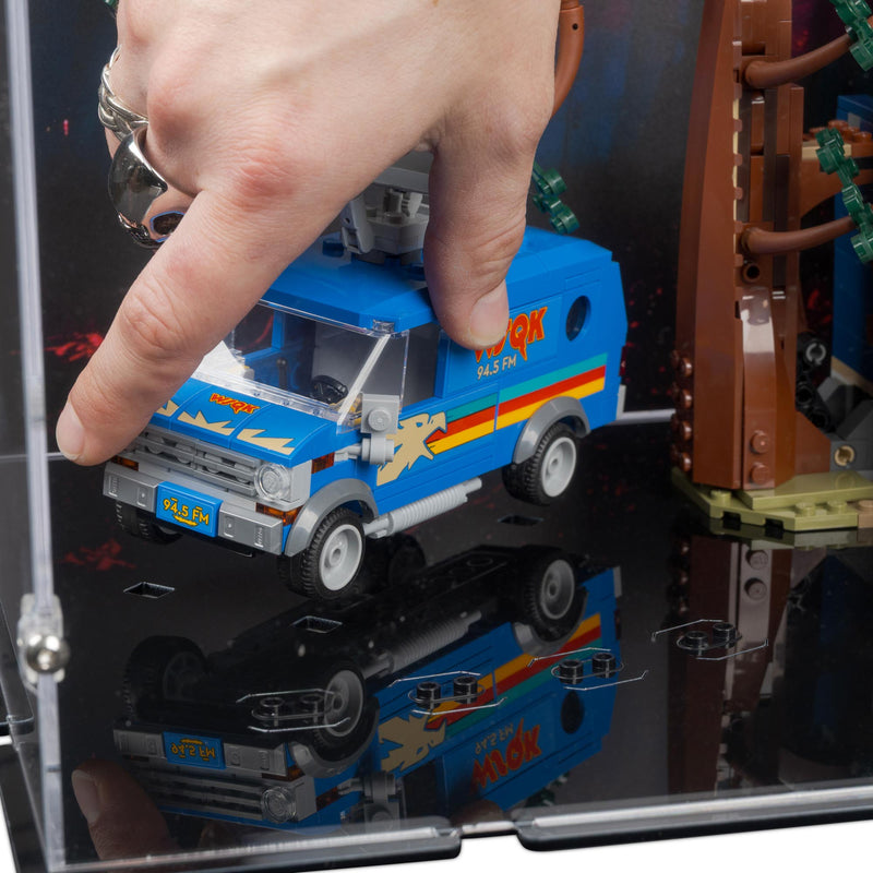Hand interacting with a lego toy truck inside a clear display case