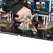 Hand placing a LEGO figure on a detailed LEGO city street scene.