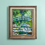 A framed art print depicting a lego Japanese garden scene with a blue arched bridge over water lilies, mounted with an acrylic wall frame.